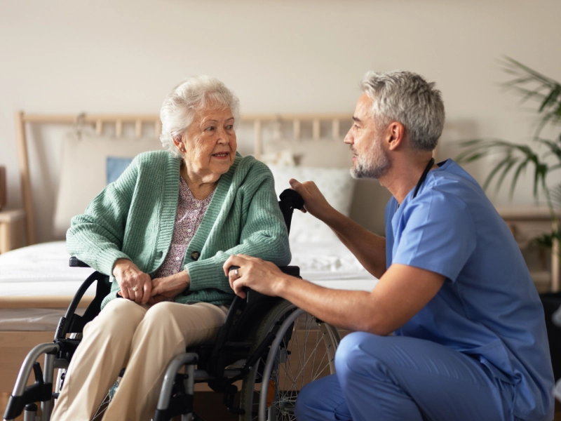 A male nurse talking to an elderly patient.